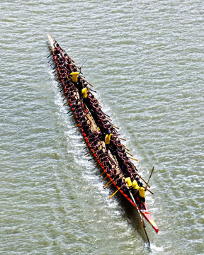 Aerial view of a traditional long boat race with many rowers in yellow shirts paddling in unison on the river in Sirajganj, Rajshahi Division, Bangladesh.