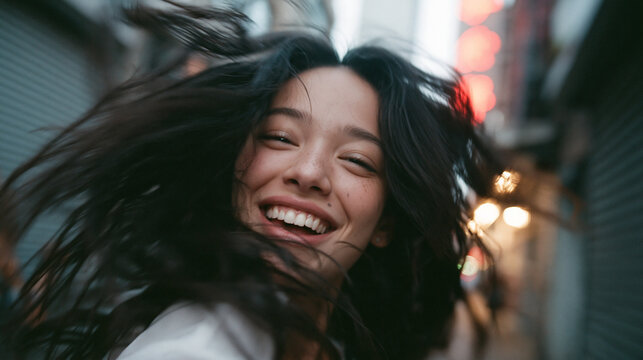 Happy Young Asian Woman Smiling with Flying Hair Outdoors