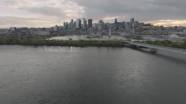 drone flying next to main bridge from park jean drapeau overlooking the city of montreal in quebec canada river old port n city