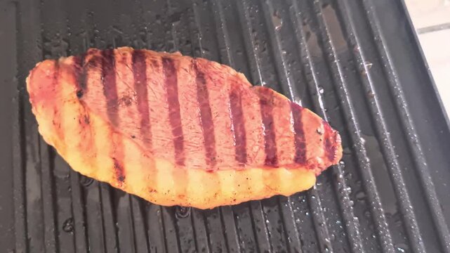 Juicy picanha steak sizzling on a hot ridged cast iron grill. Delicious thick cut beef with perfect sear marks and bubbling fat cooking to perfection.