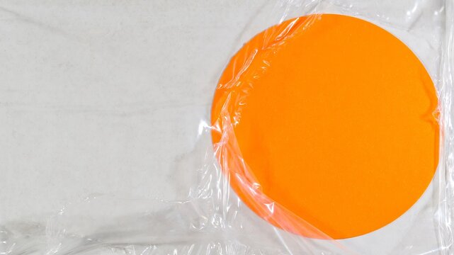 orange round circular circle paper note behind damaged torn trasparent plastic wrap foil - Bright abstract frame sticky note background backdrop