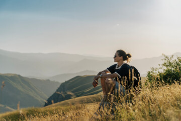 Profile portrait of serene female traveler relaxing on mountain meadow during golden hour. © olezzo