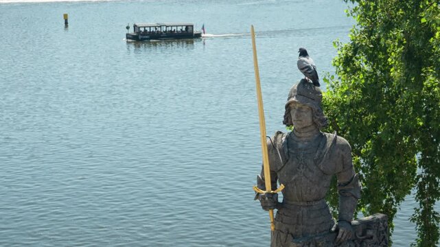 A pigeon perches on the helmet of the historic Bruncvik knight statue in Prague. Urban birds on heritage monuments highlight pest control, facade pollution, and conservation issues. 