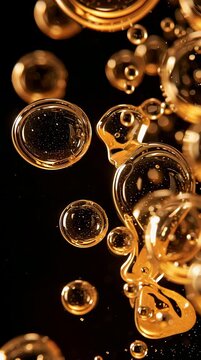 Oil droplets move through dark water, creating bright amber spots as light reflects off their surfaces in a close-up view.