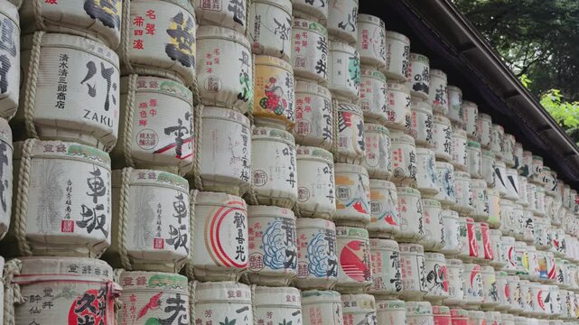 Slow-motion video panning along colorful and beautiful sake barrels at Meiji Jingu Shrine during the daytime in Yoyogi Park in Tokyo.