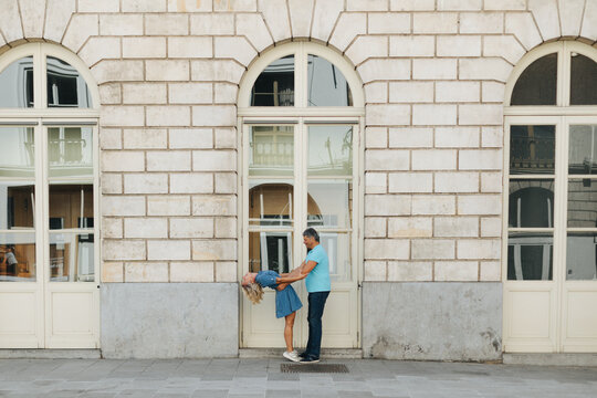 Playful couple dancing outside a classical facade