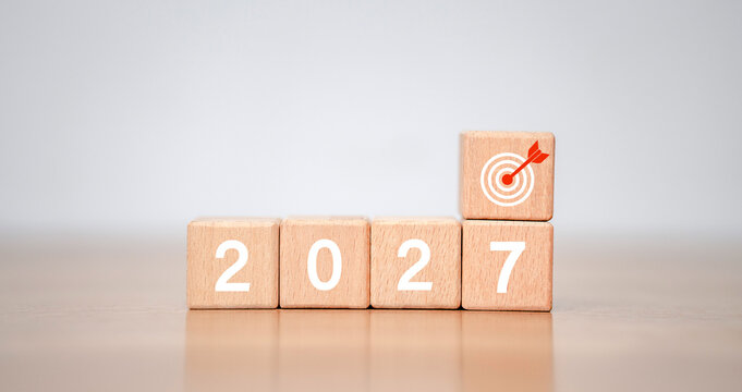 Concept of goal planning for 2027, featuring a wooden cube with the number 2027 and a dart symbol, emphasizing goal achievement, strategy, success, and growth in 2027.
