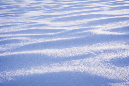 An untouched field of fresh powder snow with gentle wind sculpted