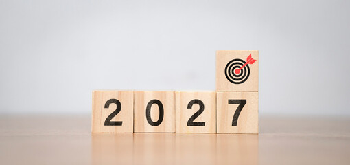 Fototapeta premium The concept of planning goals for 2027 uses a wooden cube with the number 2027 and dart symbols. It encompasses planning, review, goal setting, new beginnings, the end of the year, and New Year holida