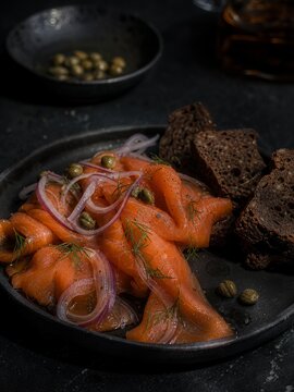 Smoked salmon lox with red onion, capers, dill and rye bread on rustic plate