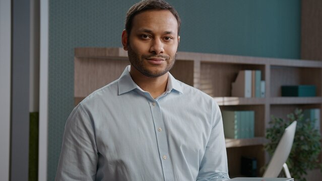 Happy Indian American business man smiling looking camera indoor office finishing online work Arabian professional entrepreneur confident manager male completed task job done workplace laptop closed