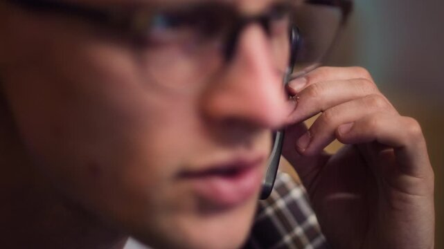 Young adult Caucasian man wearing glasses adjusting headset while staring intensely at computer screen. Footage is perfect for esports, customer service, or digital addiction campaigns