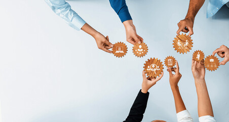 Obraz premium A diverse group of hands holding gears that symbolize teamwork, innovation, and technology in a modern business context, highlighting collaboration and mutual goals. Amity
