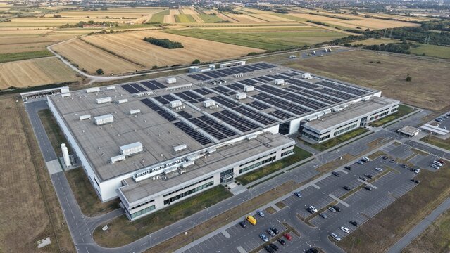 Aerial view of the industrial facility in the Severna zona with solar panels on the roof, surrounded by agricultural fields and a parking lot in Pancevo, Serbia.