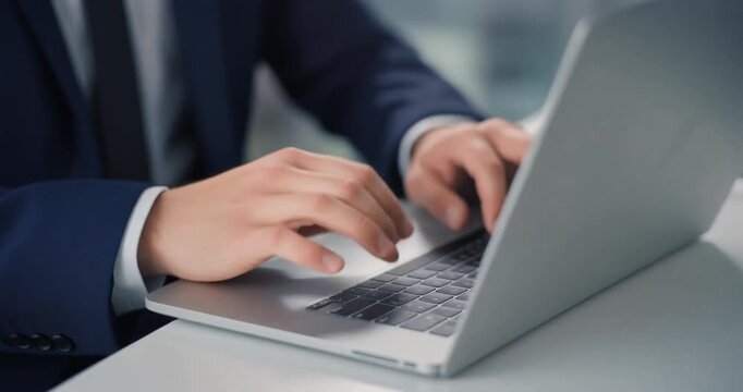 Businessman in dark blue suit typing on laptop during important work