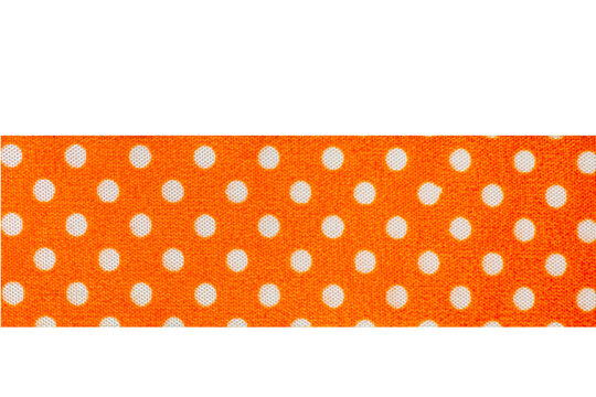 Bright orange fabric ribbon featuring a classic white polka dot pattern, isolated on a solid black background