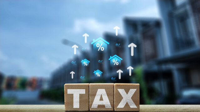 Wooden blocks spelling TAX with rising house percentage icons and upward arrows against a blurry residential background. Concept of house and property tax