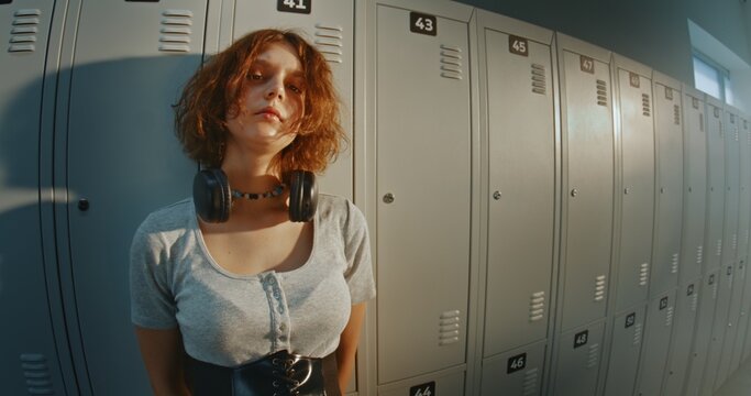 Portrait of Thoughtful Teenage Girl With Short Curly Hair Standing Near School Lockers. Introspective Mood, Solitude, Daydreaming and Authentic Adolescent Experience in a Busy High School Hallway.