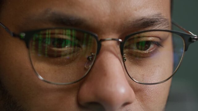 Indian American man male programmer in eyeglasses green numbers reflection coding laptop businessman looking computer screen business working crypto finance data cryptocurrency technology digital work
