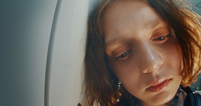 Moody Close Up Portrait of Thoughtful Teenage Girl With Slightly Tilted Head and Piercing, Looking Camera With Melancholic Expression. Emotional Depth, Vulnerability, Introspection and Coming of Age.