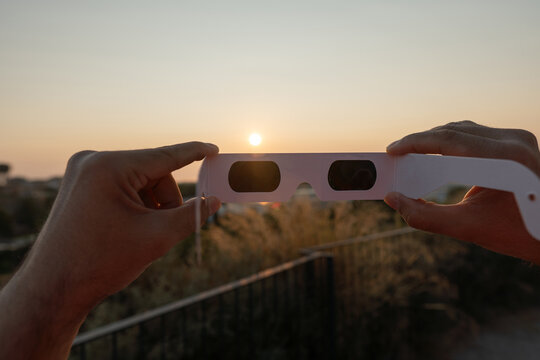 Hands holding solar eclipse glasses protecting eyes from sun