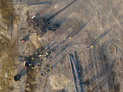 Aerial view of the Waste to Energy Facility Construction Project with workers, steel rebar bundles, and construction materials on the ground in Kecamatan Denpasar Selatan, Bali, Indonesia.