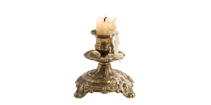 An antique brass candlestick holder with a partially melted white wax candle 