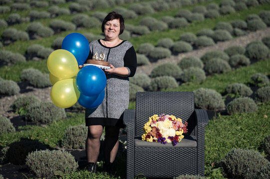 Celebrating 49 years of life among lavender fields with colorful balloons and cake in a serene outdoor setting during a beautiful day
