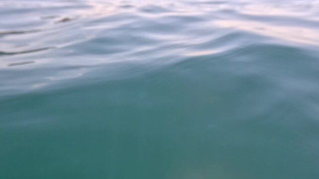 Water ocean ripples flowing across the calm surface of a clear turquoise sea to create a peaceful and serene nature background