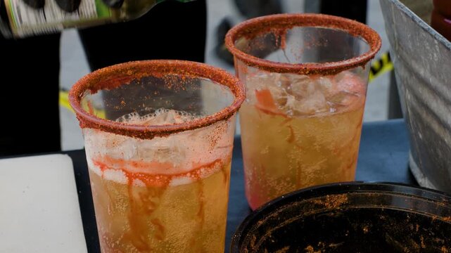 Beverage preparation footage showing man adding chamoy sauce into beer drink during preparation of a savory Mexican michelada drink