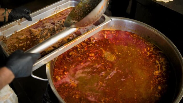 Birria cooking footage showing man ladling birria from soup pot during the traditional Mexican birria cooking process