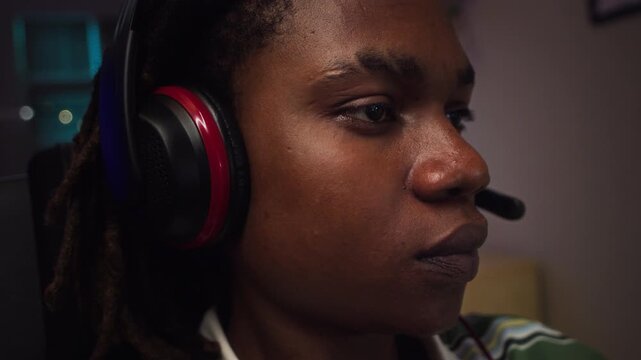 African American teenager wearing gaming headset staring intensely at screen, adjusting headphones. Clip is ideal for mental health campaigns on screen addiction or gaming industry advertisements