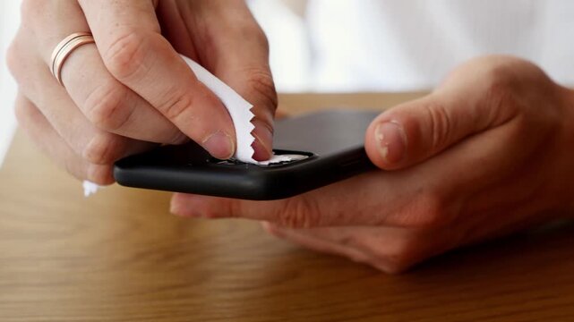 Man cleaning smartphone camera lenses with microfiber cloth for better photo quality and mobile device maintenance.