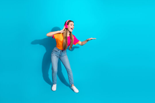 Young woman dancing with headphones on bright blue background lifestyle fashion fun energy