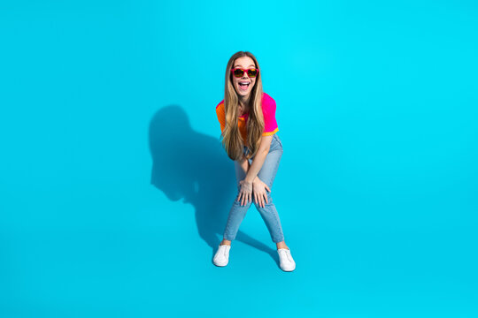 Young woman in bright shirt and jeans smiles against a vivid blue background showcasing chic fashion and lifestyle