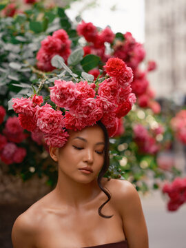Asian Woman Standing Under Blooming Pink Roses Wall