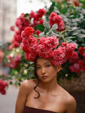 Asian Woman Standing Under Blooming Pink Roses Wall
