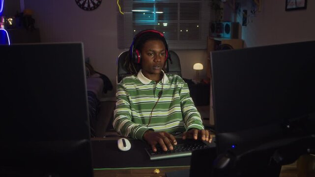 African American teenager wearing headphones typing on keyboard and playing video games on computer. Perfect for commercial use in mental health awareness or gaming industry ads
