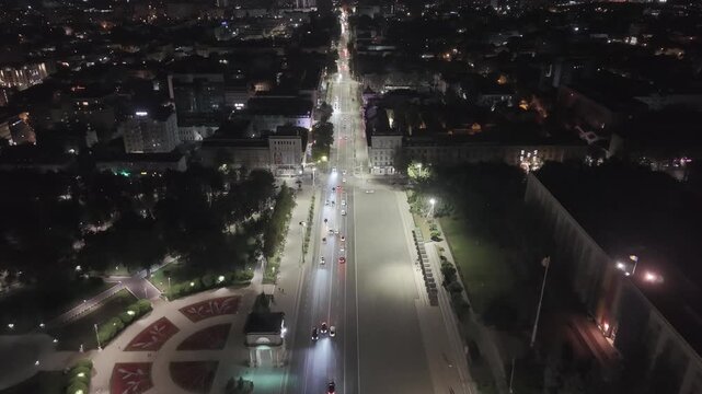 Aerial drone flight above Stefan cel Mare Boulevard in central Chisinau, Moldova at night, showing moving traffic, illuminated streets, Cathedral Park and the vibrant urban center of the Moldovan capi