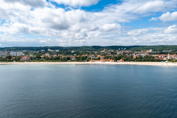 Fototapeta premium An aerial view shows the coastal town of Sopot in Poland, featuring a sandy beach, buildings along the shoreline, and the Baltic Sea.
