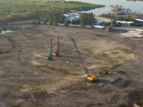 Aerial view of the Waste to Energy Facility Construction Project with heavy machinery including drilling rigs and a crane on a cleared site in Kecamatan Denpasar Selatan, Bali, Indonesia.