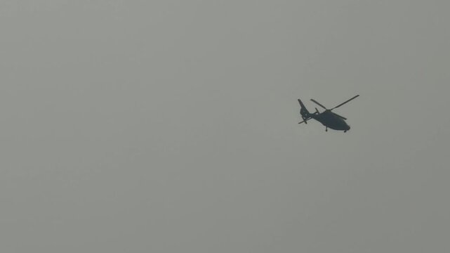A helicopter soars through a gray sky demonstrating flight capabilities and aerial transportation amidst weather conditions without the use of specialized terms or trademarks
