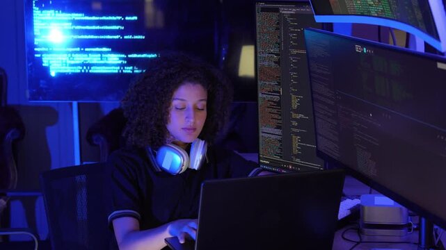 Female software developer working with multiple monitors display programming code in a modern technology workspace. coding, cybersecurity, digital technology, data processing, programming, innovation.