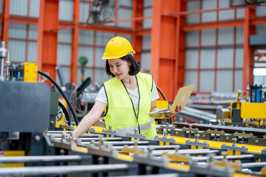 Woman engineer wearing protective equipment working on a laptop in a contemporary manufacturing environment