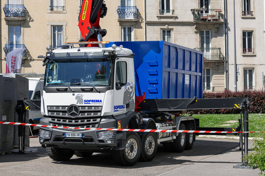 Nancy, France - June 1st 2021 : View on a white Ampliroll truck Mercedes-Benz Arocs with a removable blue roll-off skip parked on a construction site with buildings in the background.