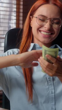 Happy carefree Caucasian business woman throwing cash money rain at office table excited rich businesswoman throw salary banknotes joyful female girl executive fooling around with finance in company
