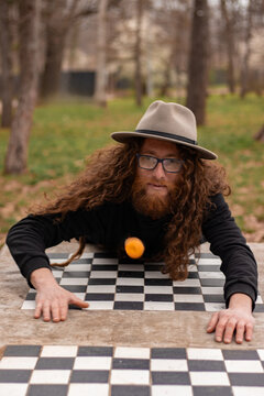 Hippie Man Drawing On Checkered Surface While Meditating Outdoors