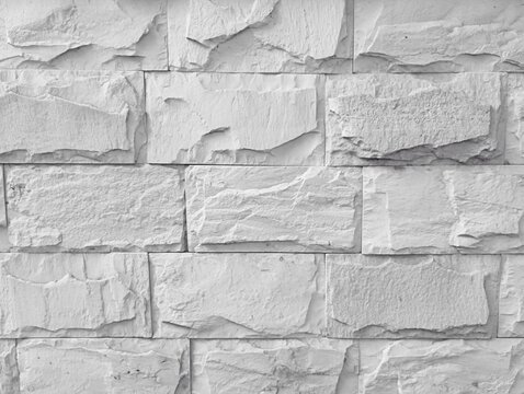 Abstract white cladding stone tile wall texture background with a coarse relief surface structure and light shadows, ideal for a modern architectural interior or brickwork backdrop.