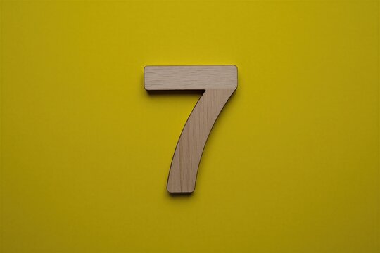 Wooden number seven sits on flat bright yellow surface background. Small timber digit seven placed centrally for visual appeal. Minimalist design object creates clean aesthetic perfect for birthday