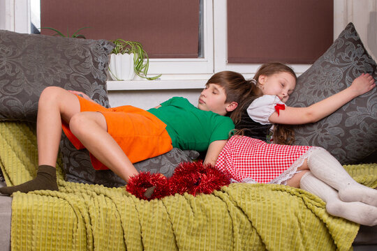 Children sleeping peacefully on a couch with decorative pillows